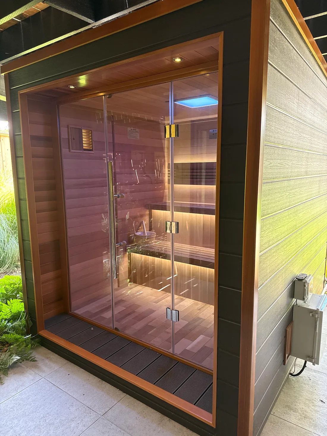 A glass-fronted sauna with light under the benches