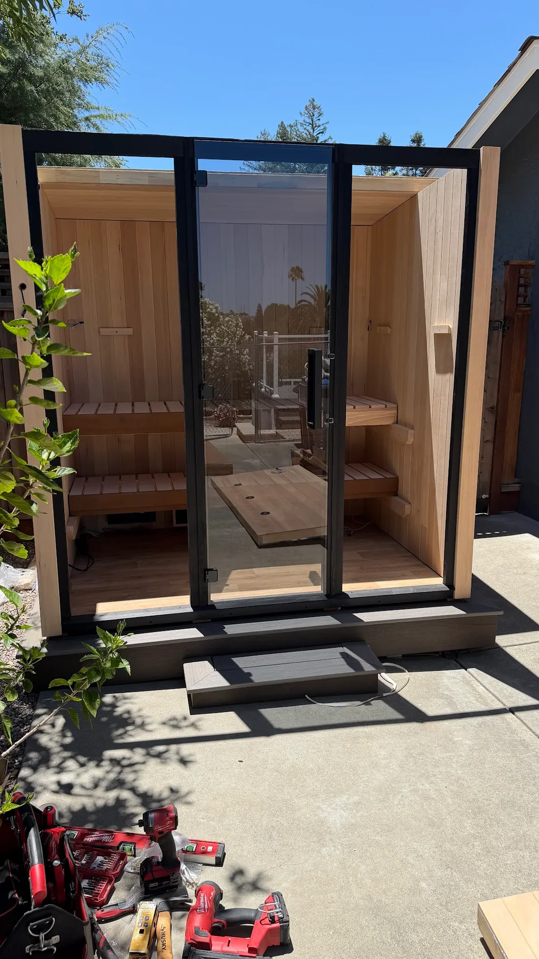 An outdoor sauna with its glass doors open onto a step, San Jose