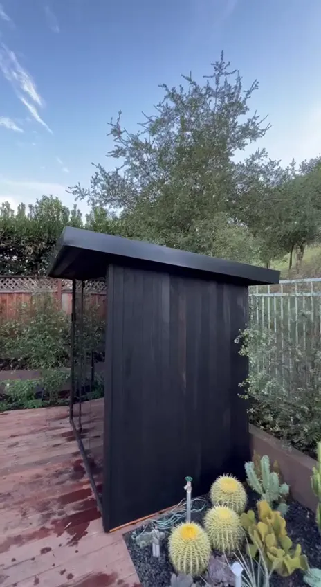 A black-clad outdoor sauna in a garden
