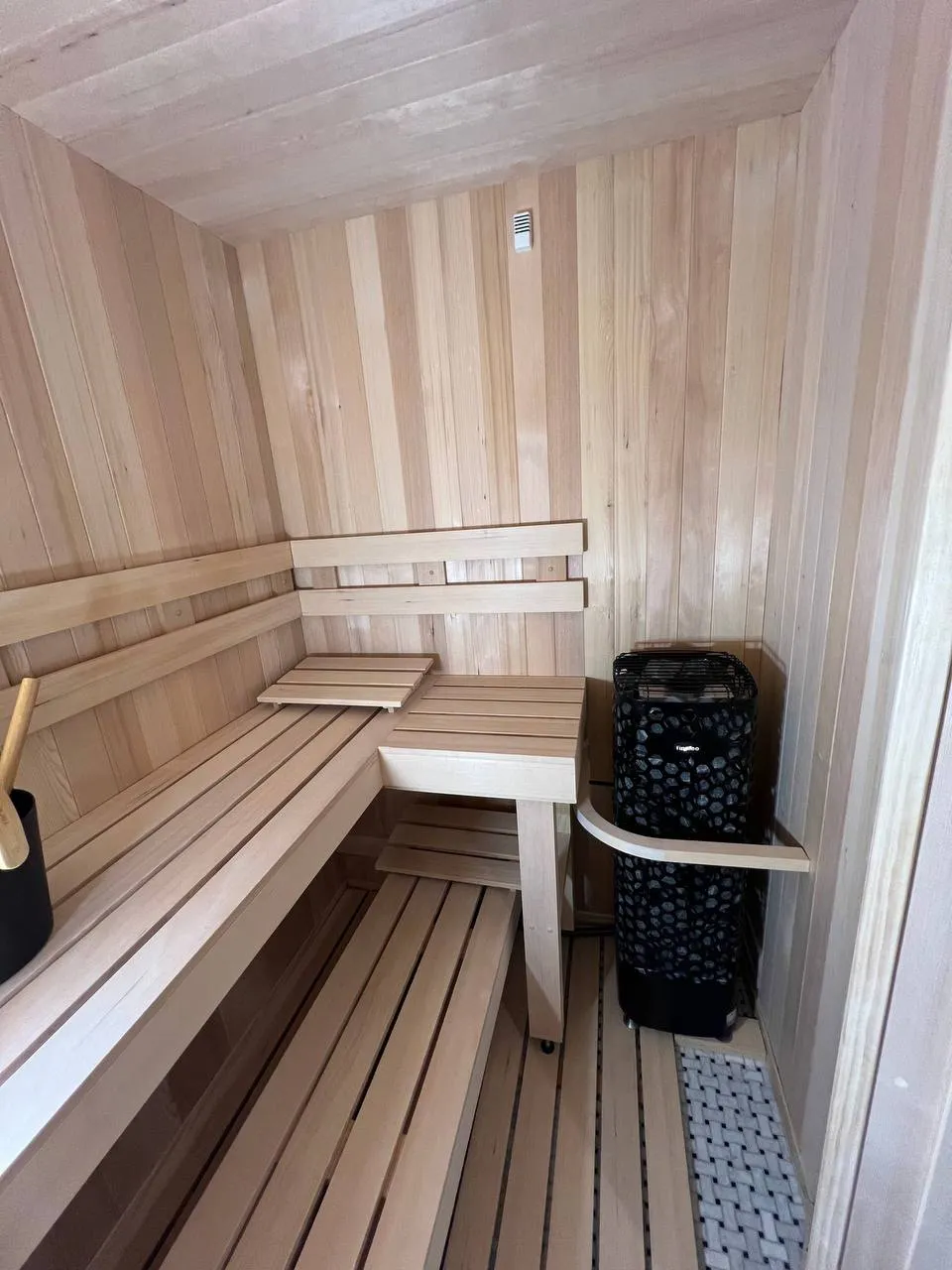 An L-shaped bench in a light cedar room with the heater in the corner