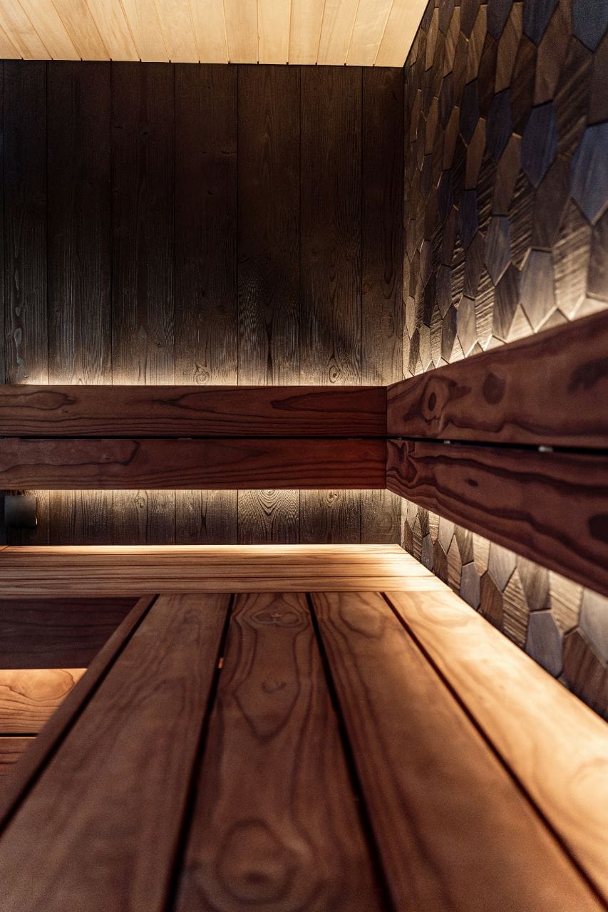 Dark charred-cedar sauna benches and a shingle-clad wall